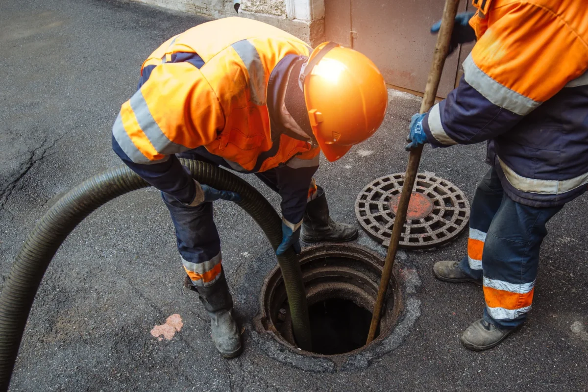 Drainage workers attending an open sewer access chamber.