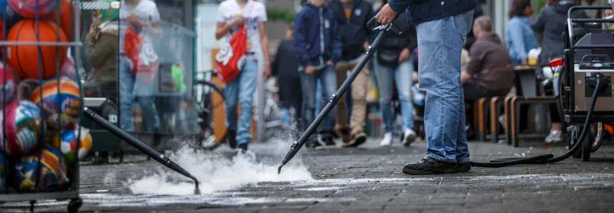 Street-cleaning crew directing steam jets at marked paving